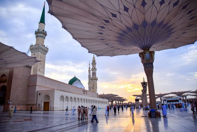 Open shade umbrellas over the courtyard of Masjid an-Nabawi in Madinah at sunset.
