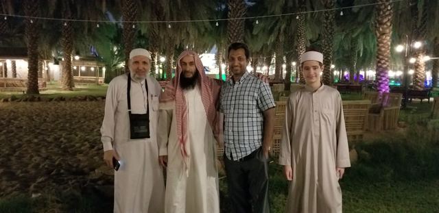 Four Amity travelers at night in a garden lit among palm trees