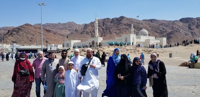 Amity Umrah group at Uhud with the white Sayyid al-Shuhada Mosque and red mountains behind