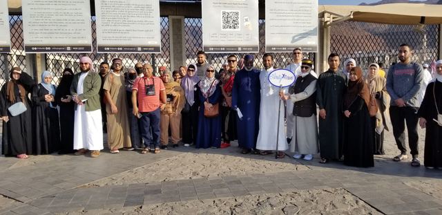 Large Amity Umrah group in front of the information boards at the Uhud martyrs' cemetery