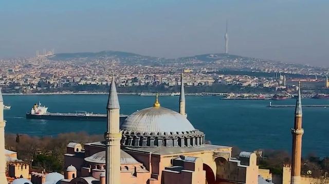 Aerial view of Hagia Sophia's dome and minarets with the Bosphorus and the Istanbul skyline behind.