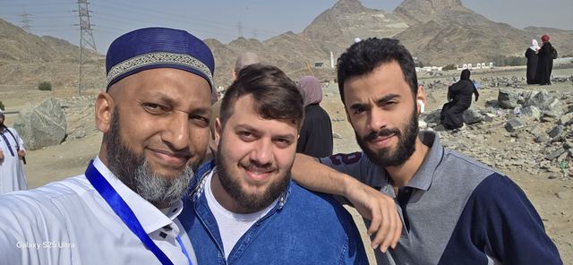 Amity group leader taking a selfie with two travelers, mountains behind