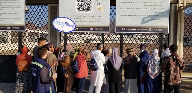 Amity travelers reading the information boards at the Uhud martyrs' cemetery, Amity sign raised